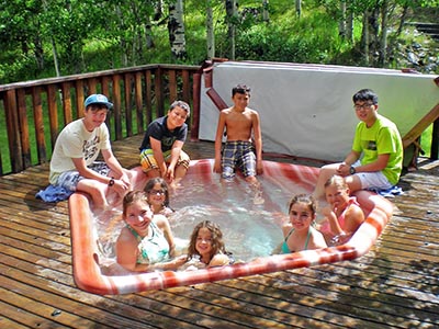 Children and teens relax in and around the hot tub on the Red Creek Lodge’s back deck.